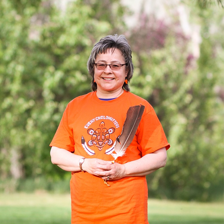 Phillis wearing an orange t-shirt while holding a feather