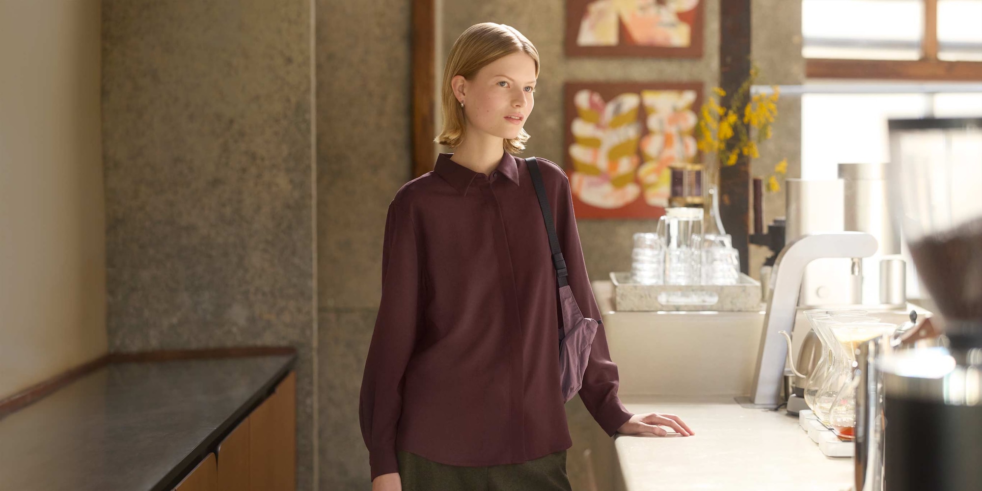 model wearing wine blouse with dark grey trousers and a light purple shoulder bag