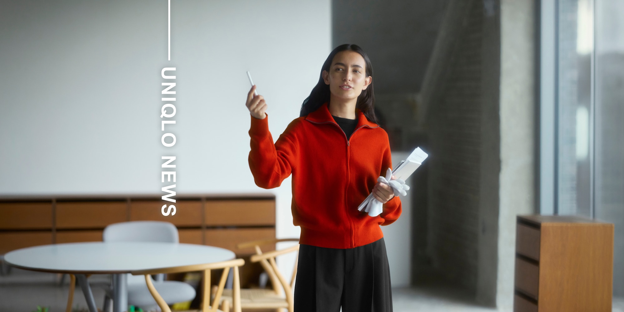 Model trägt rote Strickjacke, schwarzes T-Shirt und schwarze Hosen.
