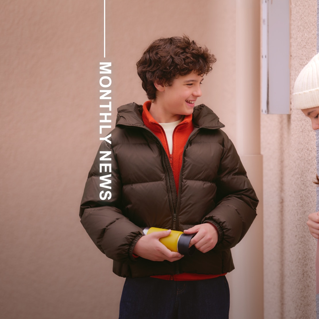 model wearing white T-shirt, orange zip-up top and brown down jacket overlaid with the words monthly news