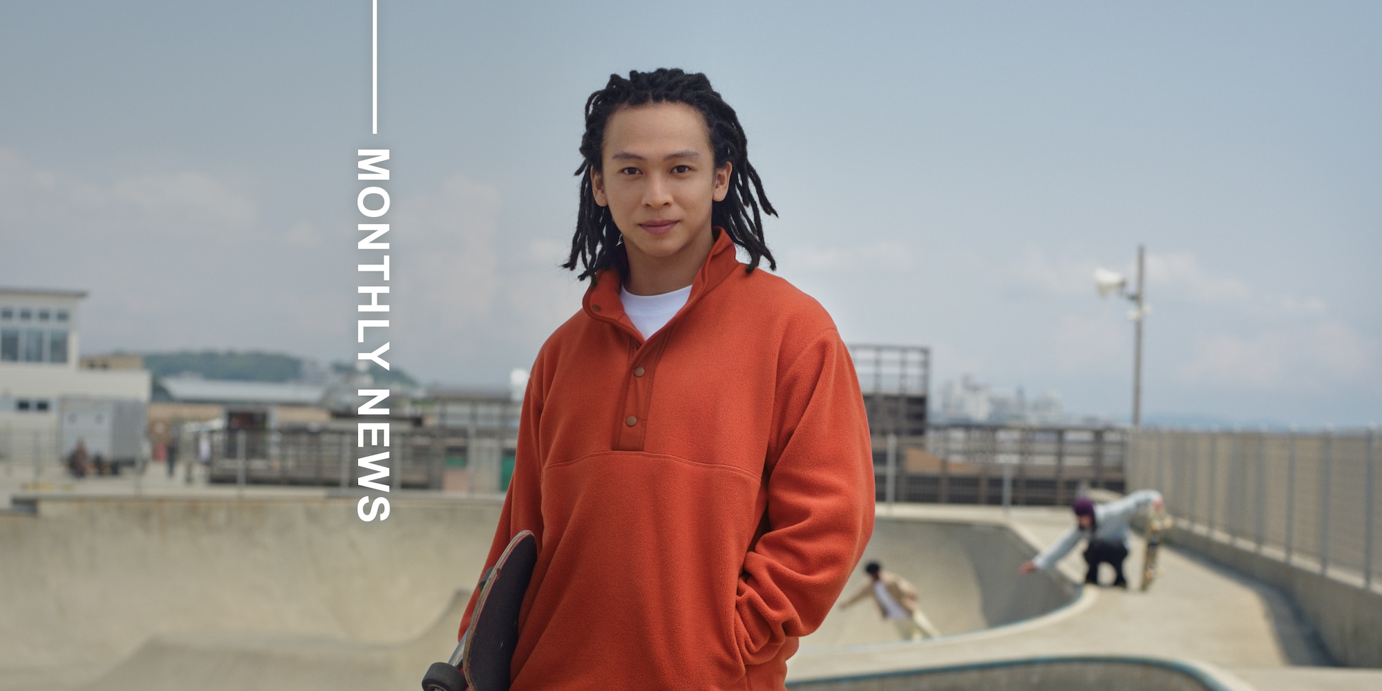 Professional Skateboarder & Snowboarder Ayumu Hirano wearing an orange button-up fleece pullover and holding a skateboard