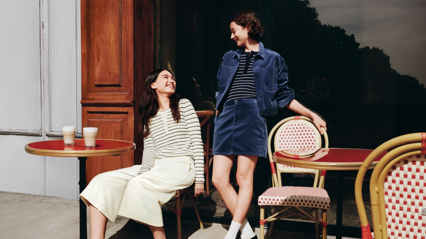two models wearing UNIQLO and COMPTOIR DES COTONNIERS Autumn/Winter 2026 Collection​ while outside a Parisian café