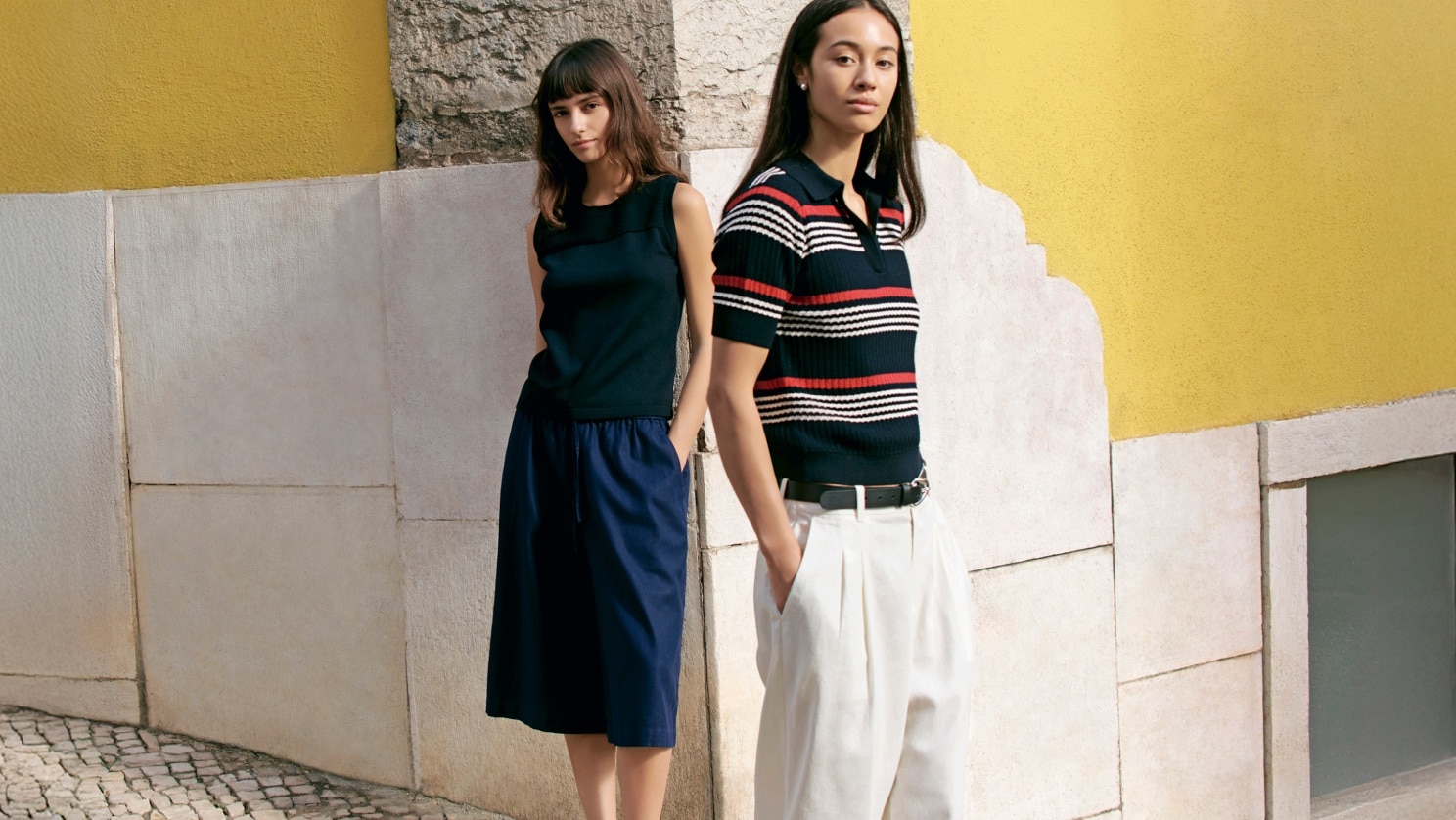 two models wearing UNIQLO and COMPTOIR DES COTONNIERS Spring/Summer 2026 Collection stood against a wall painted bright yellow