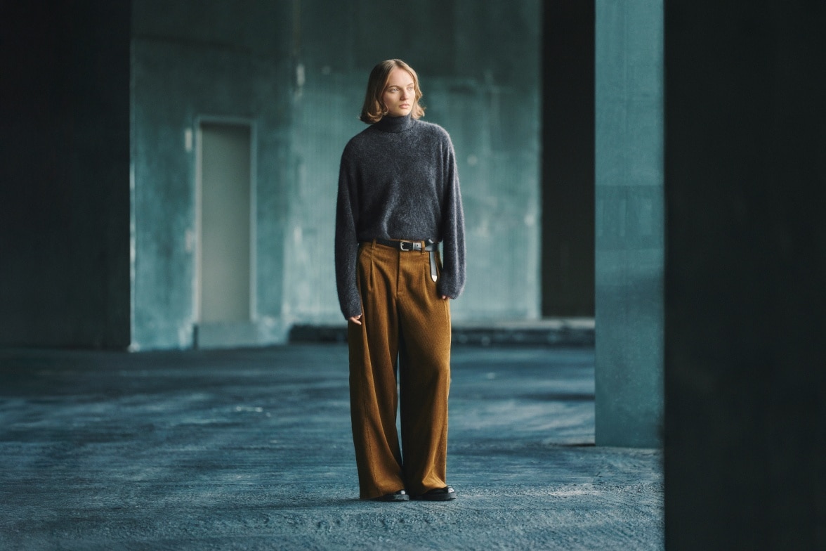 model wearing a grey jumper with rust coloured trousers