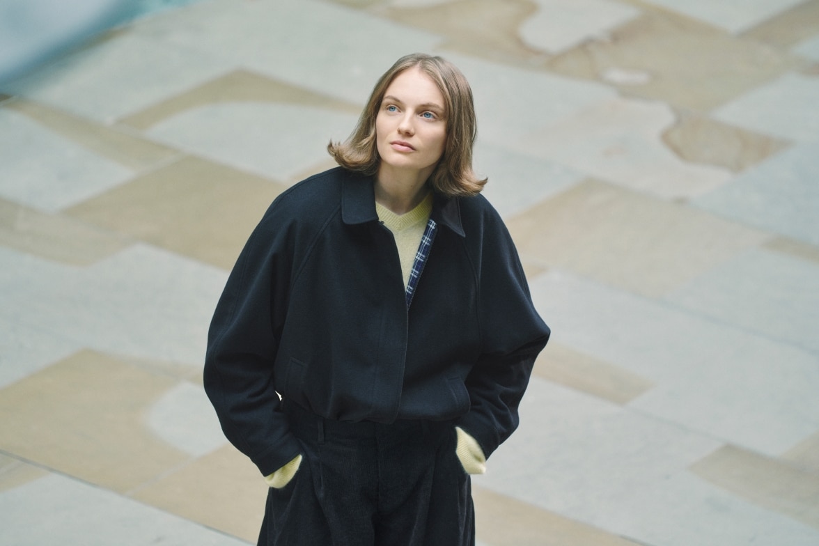 model wearing jacket over a pale yellow top and dark trousers