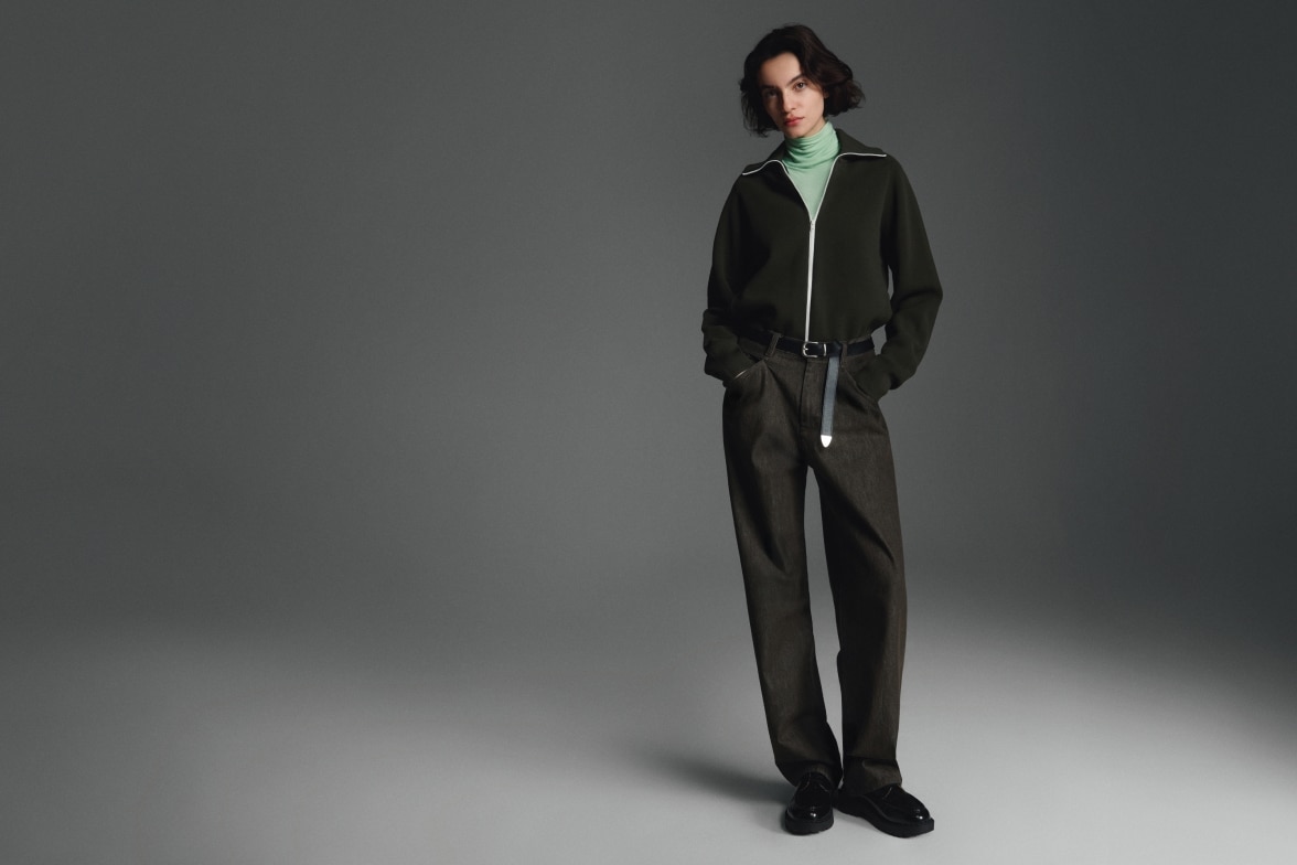 model wearing pale mint green HEATTECH turtleneck under a dark green zip-through cardigan with dark trousers