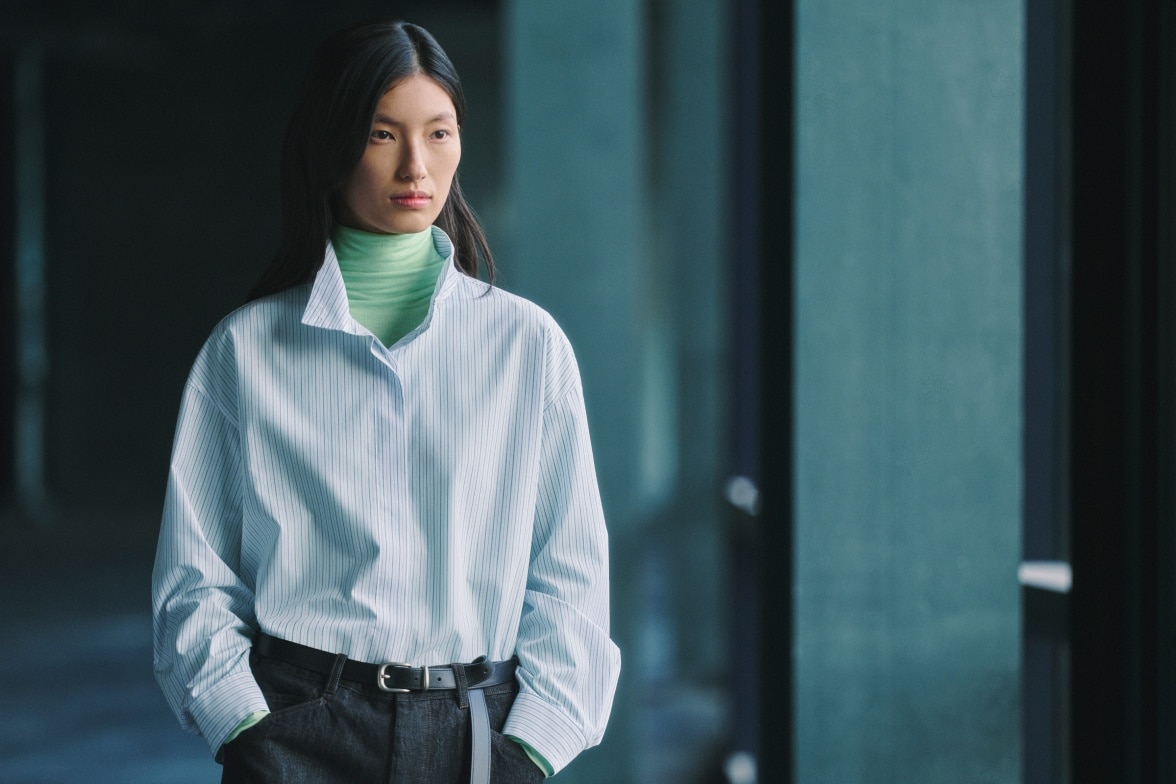 model wearing light blue shirt over a pale mint green turtleneck thermal top with dark trousers