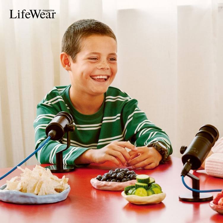 Cedar wearing AIRism Cotton Crew Neck T-Shirt in green and white stripe while sat at a red dining table with microphones and snacks