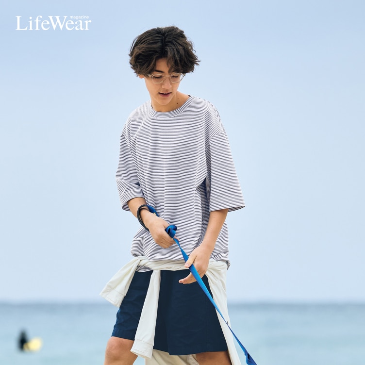 model wearing AIRism Cotton Oversized Crew Neck T-Shirt, Chino Shorts, Socks and DRY-EX UV Protection Full-Zip Hoodie while walking a dog on the beach