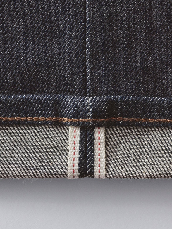 close-up of the turned up hem of a pair of selvedge jeans to show the signature red ear selvedge