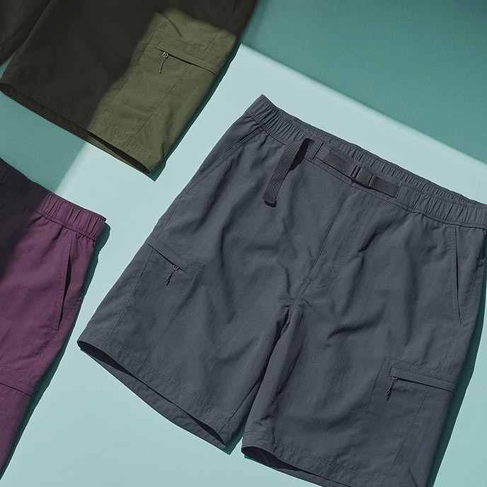 three pairs of Geared Shorts in olive, maroon and dark grey laid flat on a light blue surface