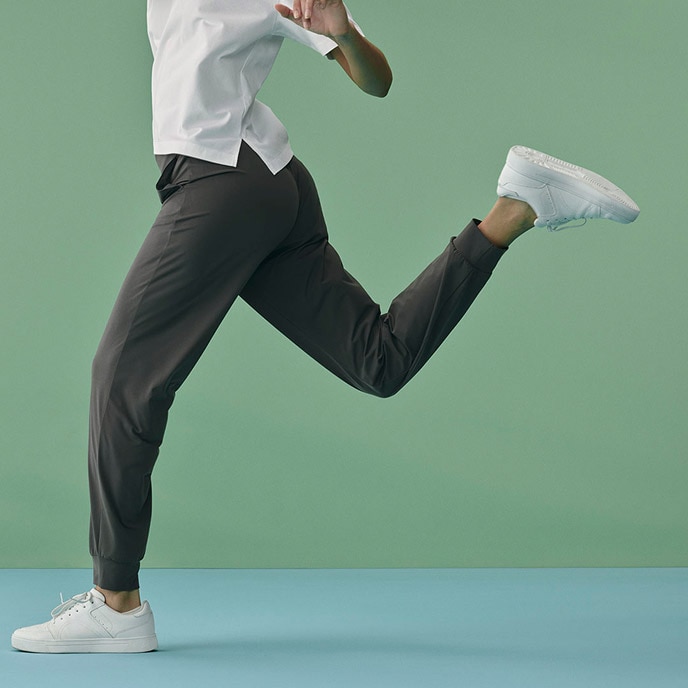 model wearing Ultra Stretch Joggers in dark grey with a white T-shirt and trainers, mid-run
