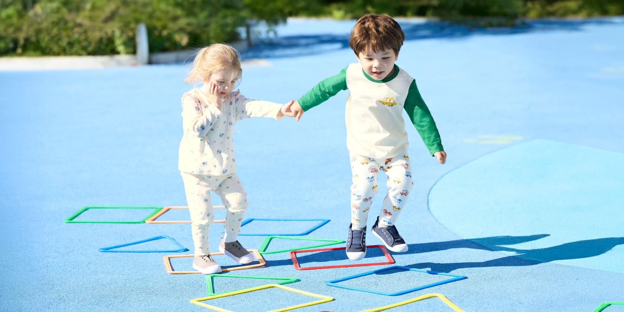 two models holding hands while playing outside wearing UNIQLO clothing for toddlers