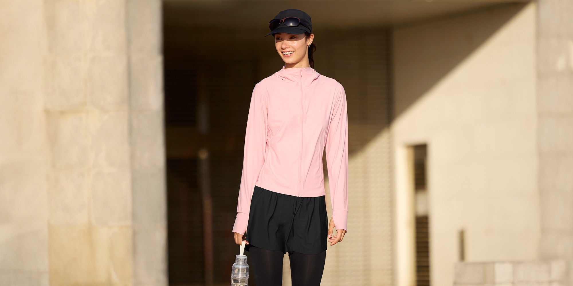 model wearing Ultra Stretch AIRism UV Protection Full-Zip Hoodie in pink with black Ultra Stretch UV Protection Active Leggings and Ultra Stretch Active Shorts in black over the top