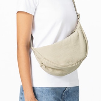 model wearing a white T-shirt and blue jeans with a beige Round Mini Shoulder Bag