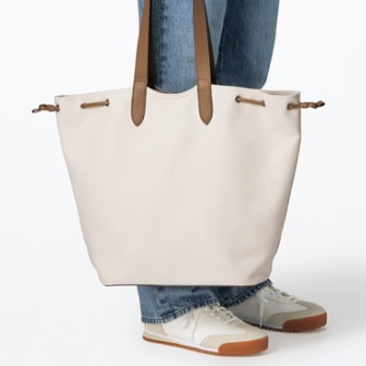 model wearing blue jeans carrying a Canvas Tote Bag in off white