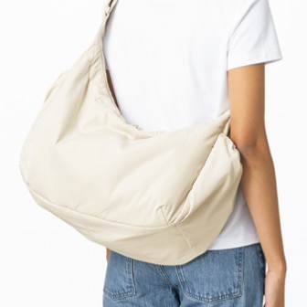 model wearing a white T-shirt and blue jeans with a Puffy Shoulder Bag in cream