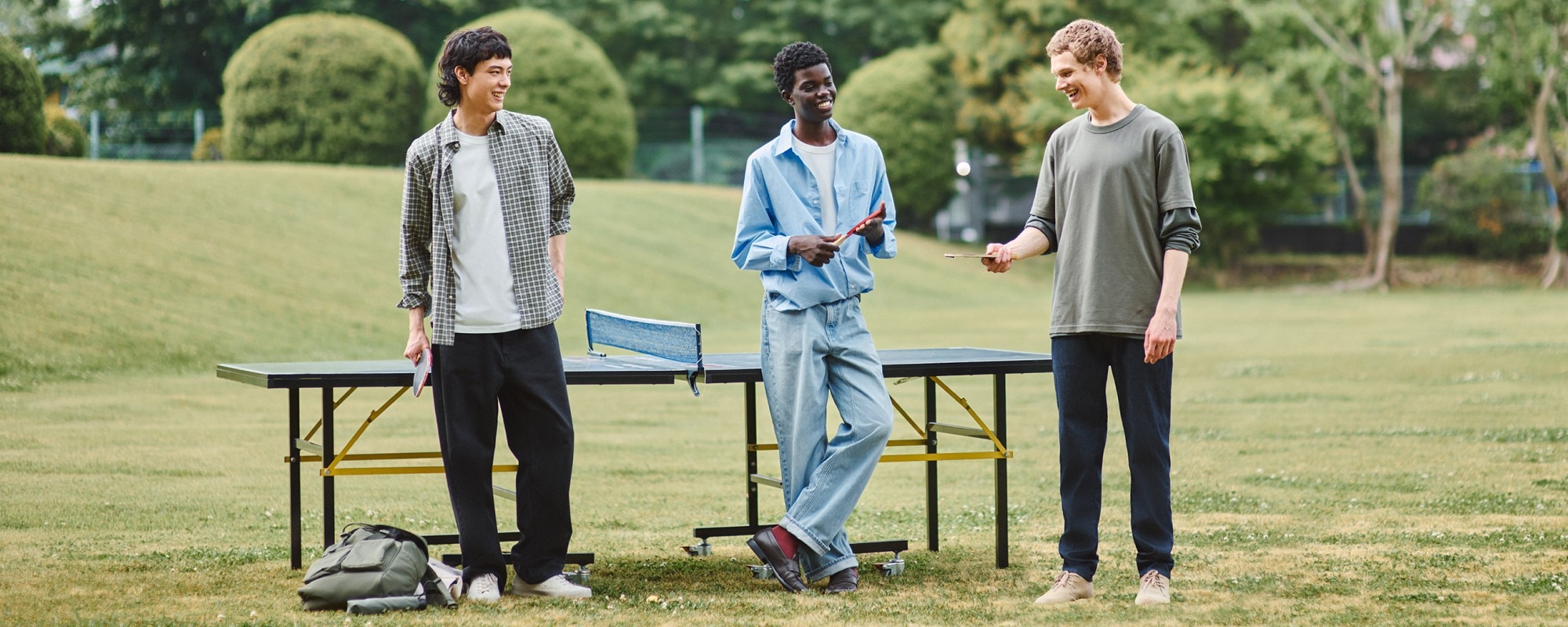 three models playing table tennis outside wearing UNIQLO jeans styled with shirts and T-shirts
