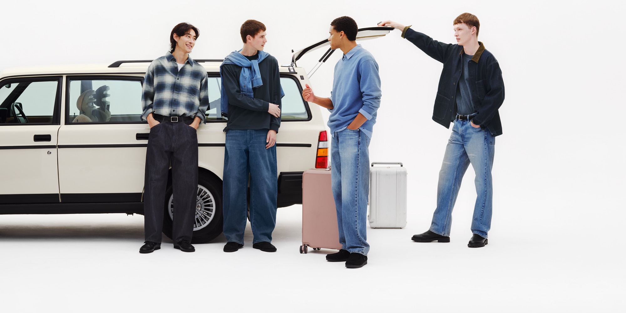 four models wearing uniqlo jeans while packing the boot of a white estate car with suitcases