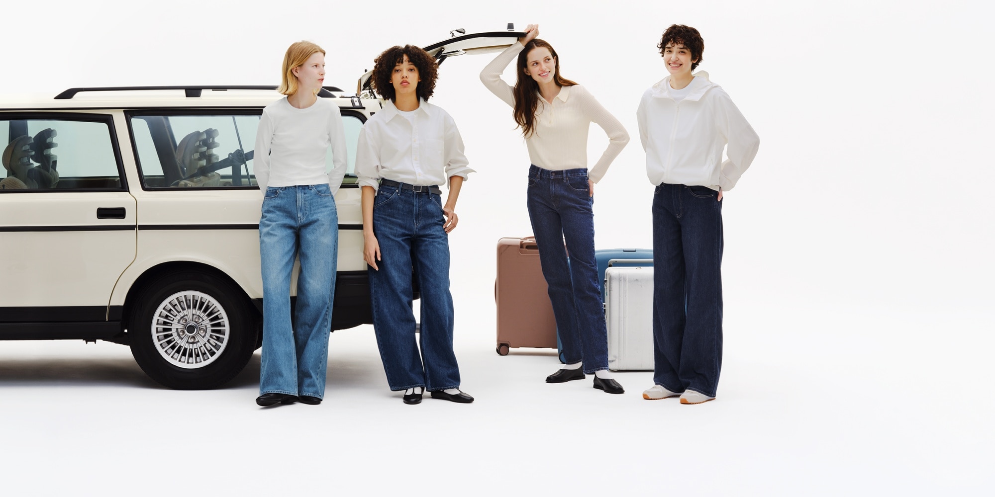 four models wearing uniqlo jeans while packing the boot of a white estate car with suitcases