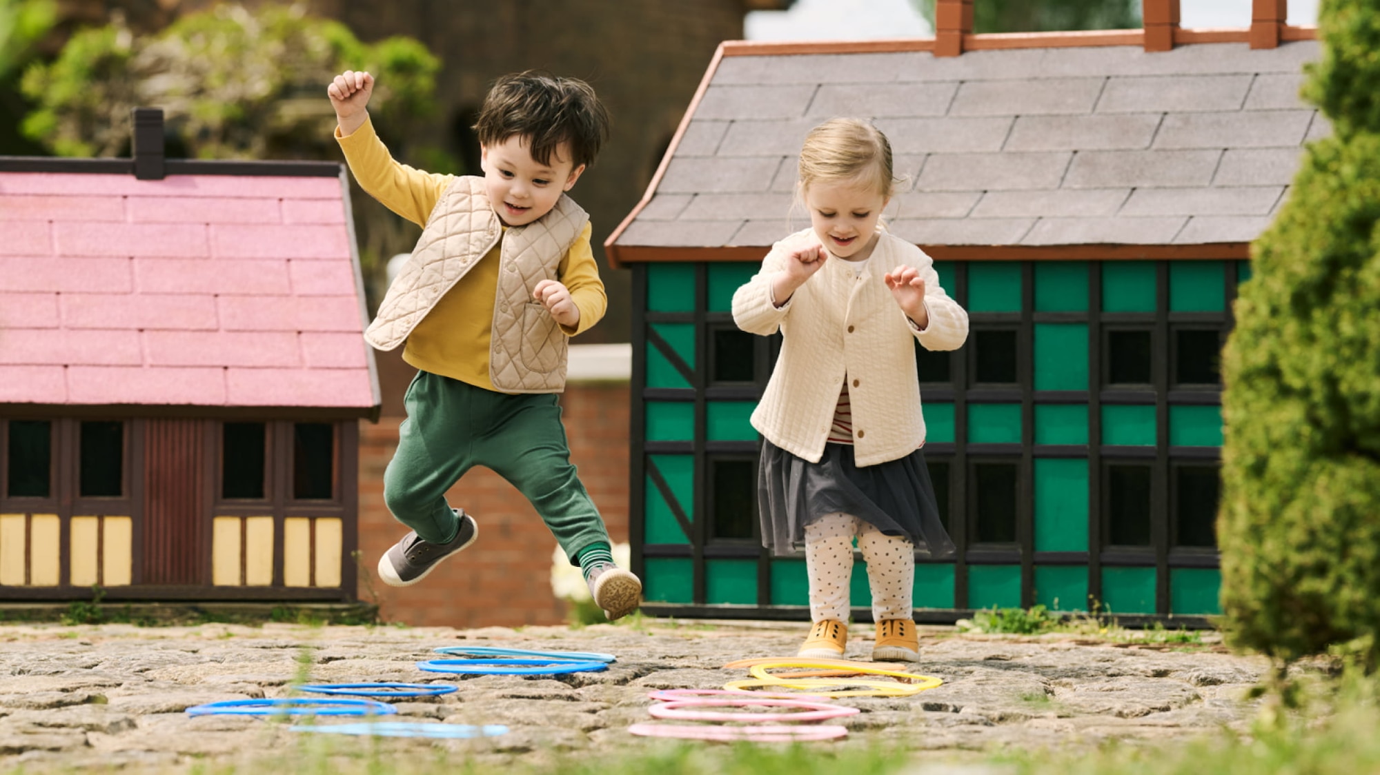 two models wearing UNIQLO clothing for toddlers playing outside