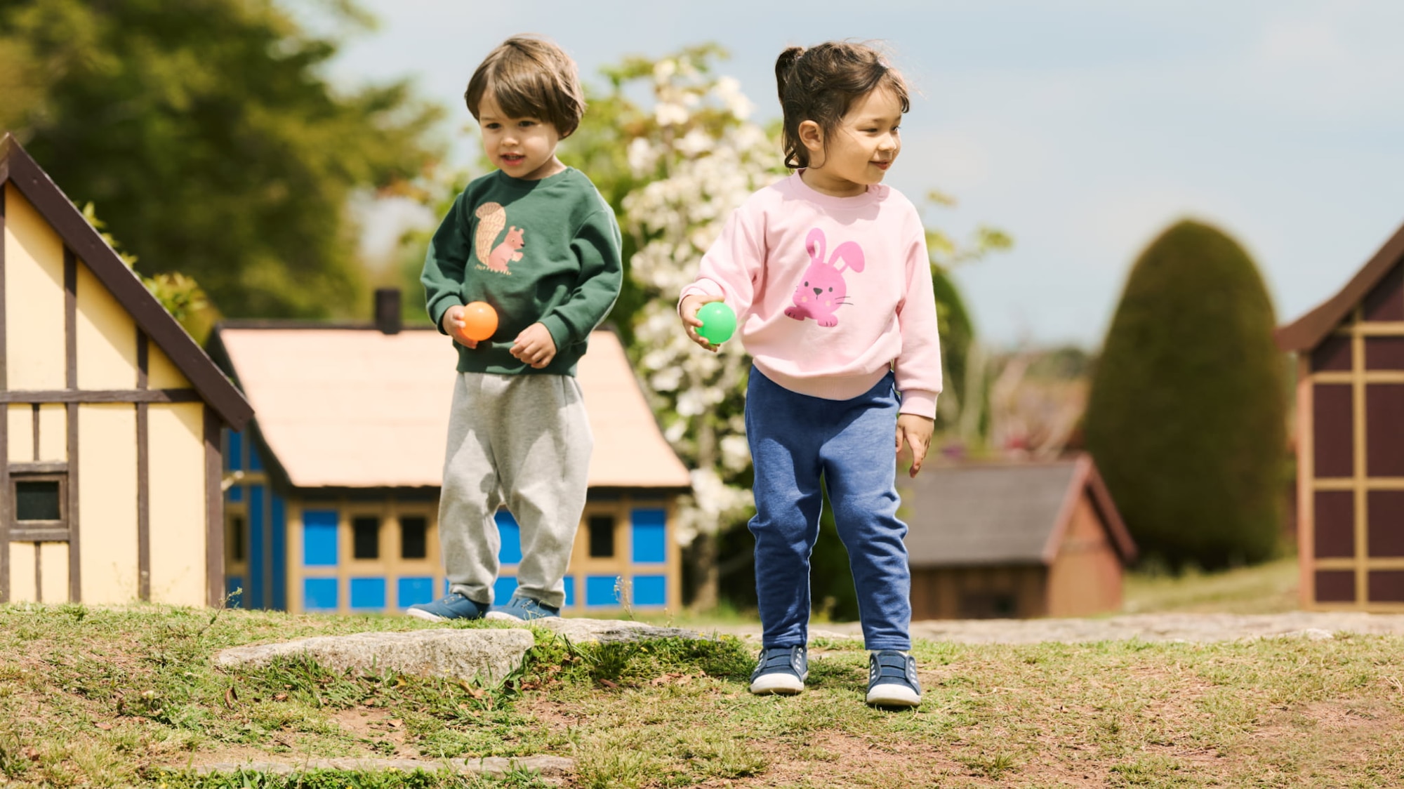 two models wearing UNIQLO leggings while playing with balls outside