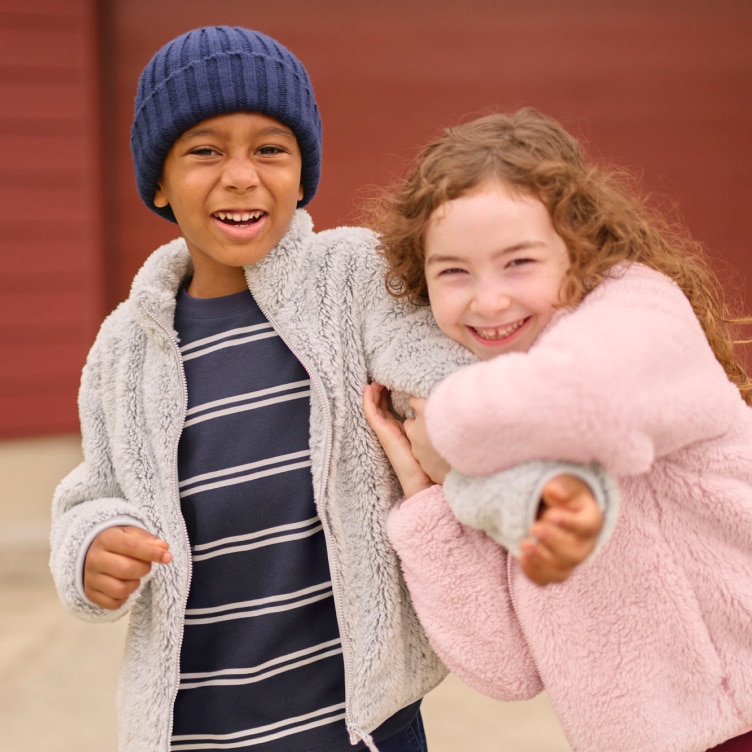 two models wearing fleece jackets in grey and pink while holding onto each other