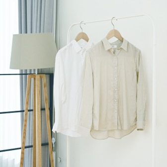 two linen shirts in white and beige, drying indoors on hangers