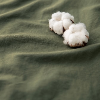 close-up of Cotton Linen fabric in khaki with two cotton balls on top