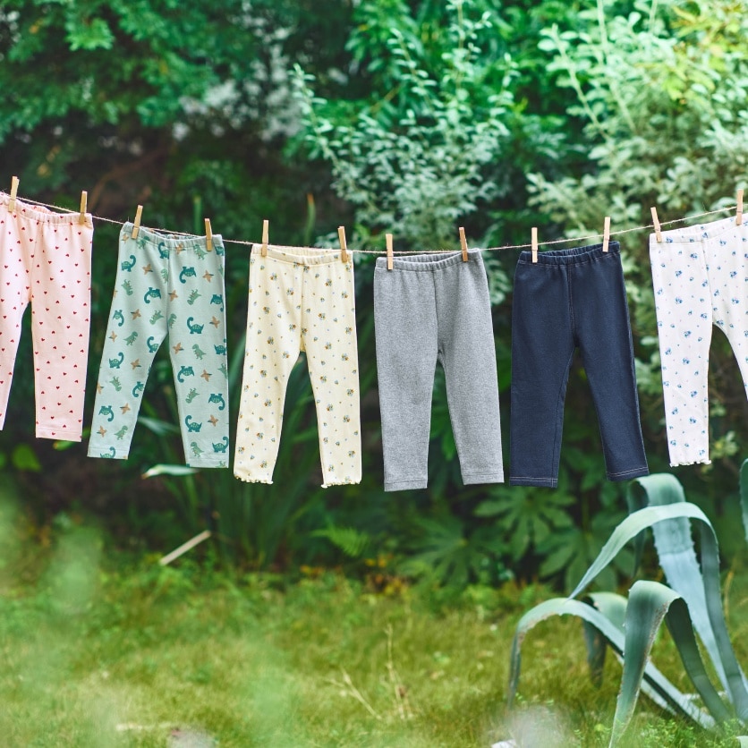des leggings UNIQLO accrochés avec des pinces à linge sur un fil à l'extérieur.