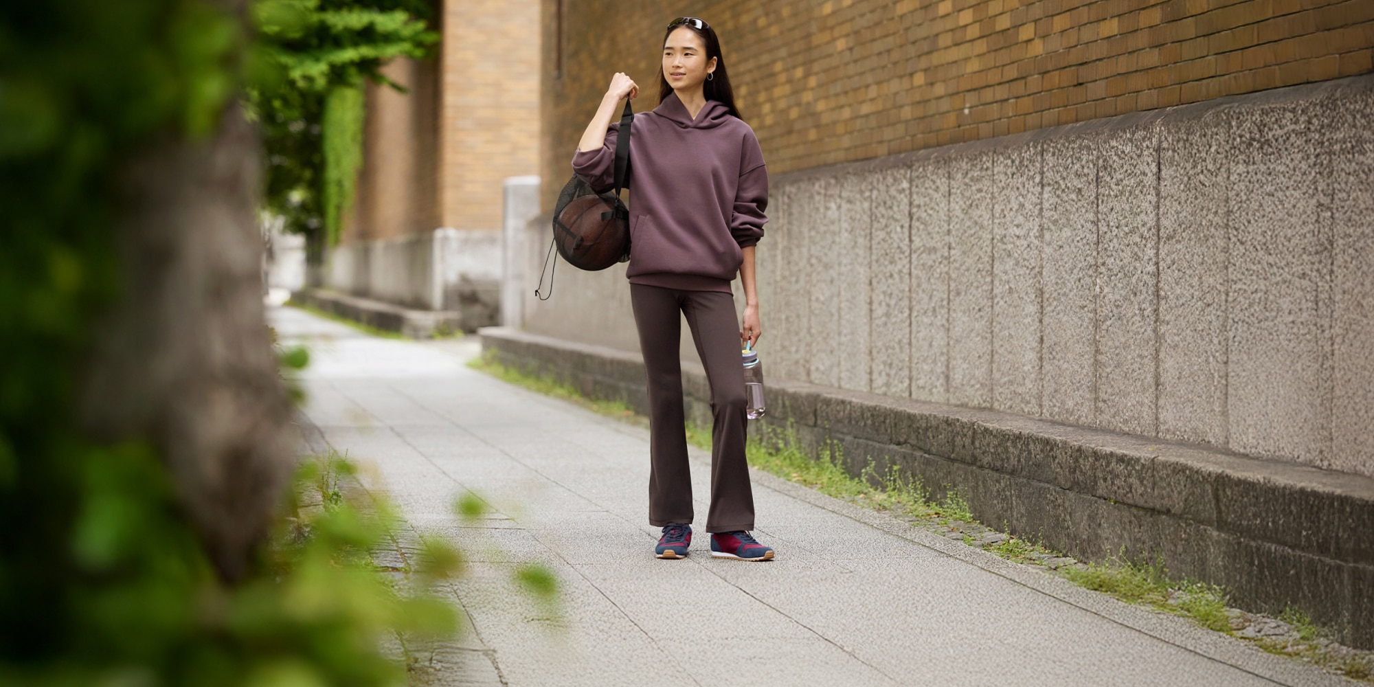 Model wearing Sport Utility Wear hoodie and leggings, carrying workout essentials.