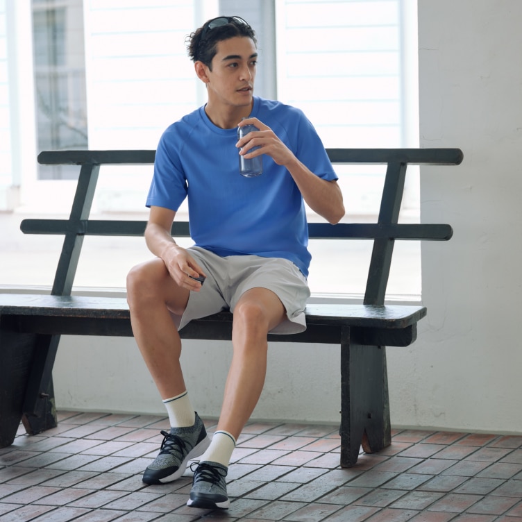 model wearing Sports Half Socks, DRY-EX T-Shirt and Ultra Stretch Active Shorts while sat on a bench with a drink