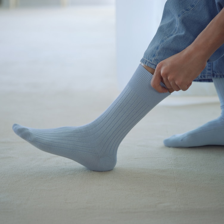 model pulling on Supima Cotton Blend Socks in light blue