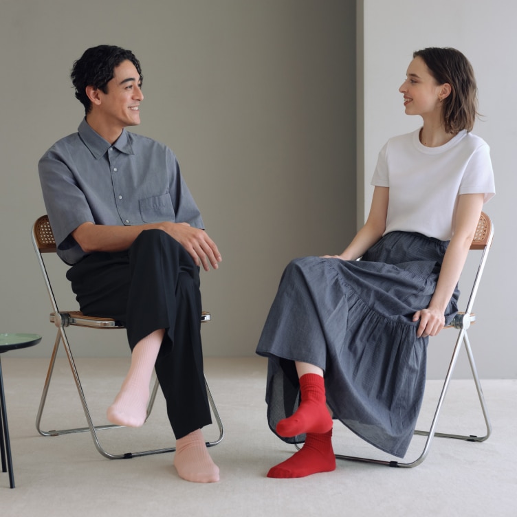 two models sat facing each other on chairs wearing socks without shoes