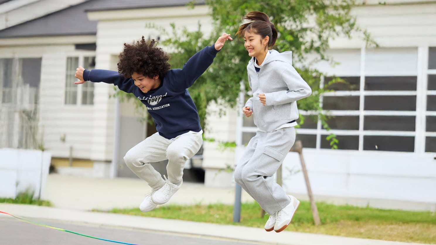 two models wearing UNIQLO sweats while jumping over a skipping rope