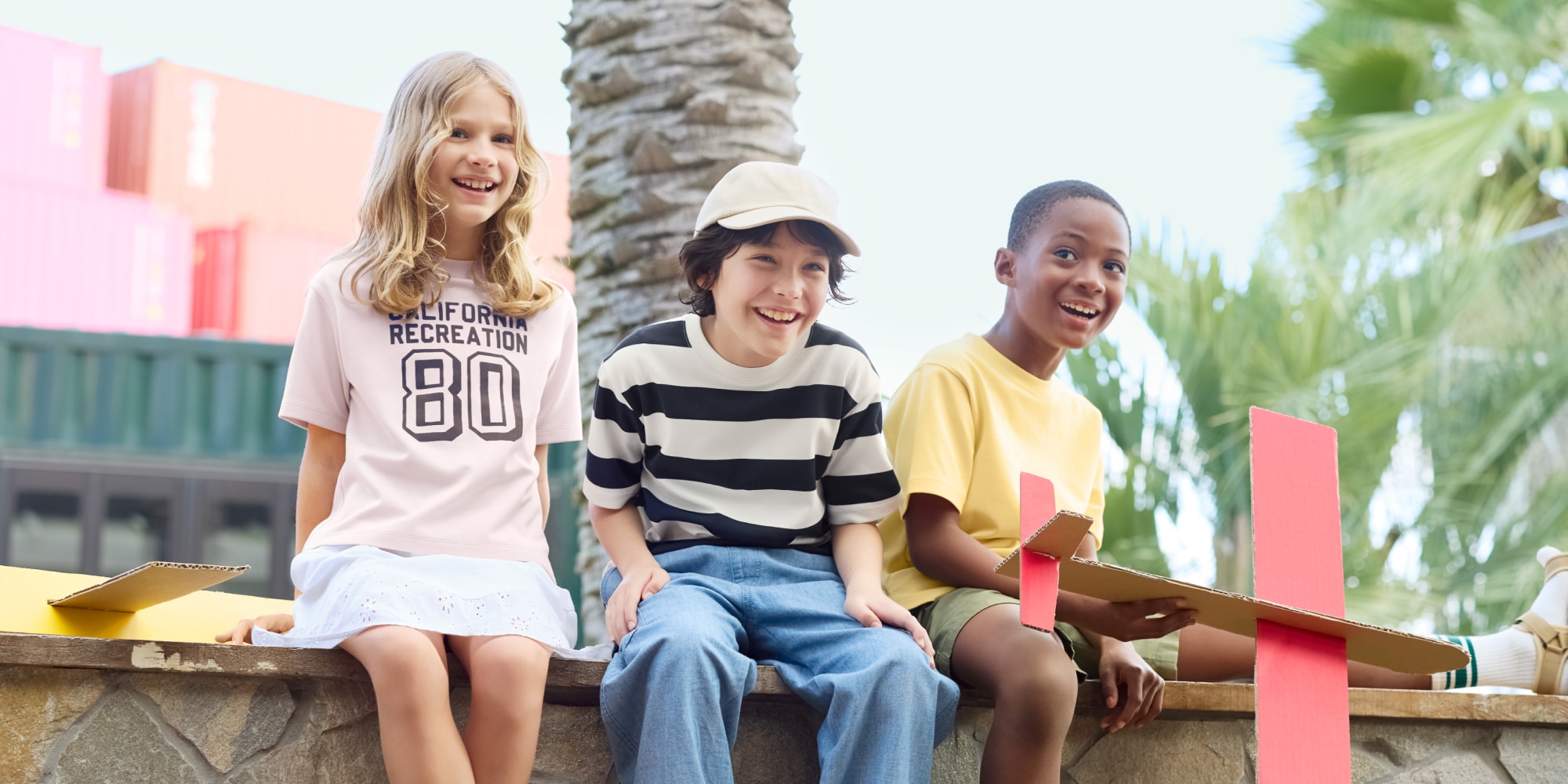 three models sat holding model airplanes while wearing UNIQLO T-shirts
