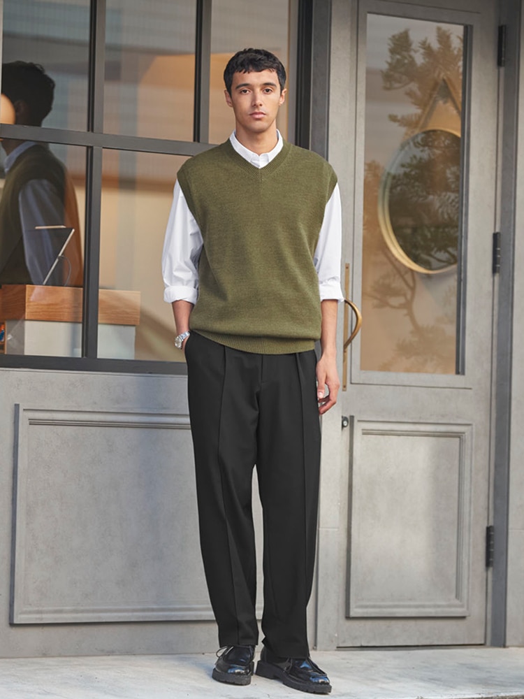 model wearing a white shirt under an olive sweater best with black trousers and shoes
