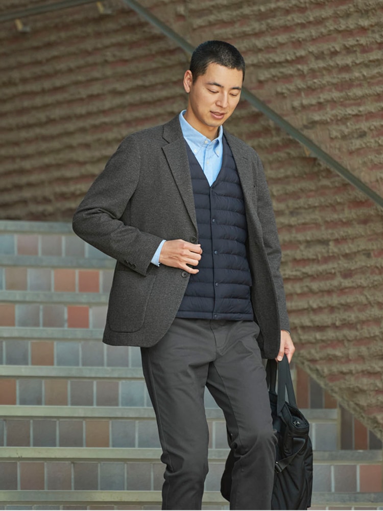 model wearing a grey suit with a navy quilted vest and light blue shirt underneath the jacket