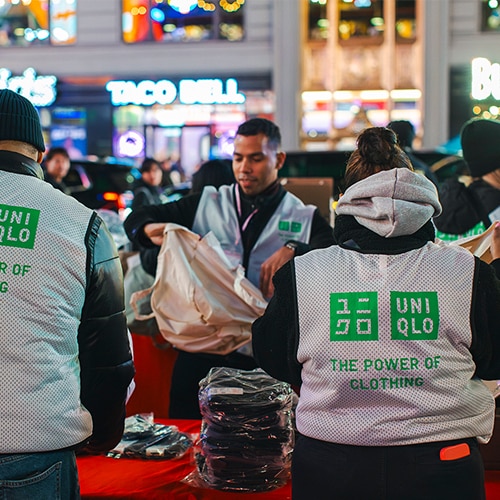 UNIQLO Staff volunteers packing clothing outside in New York City. Volunteers are wearing a white mesh vest with "The power of clothing" print.
