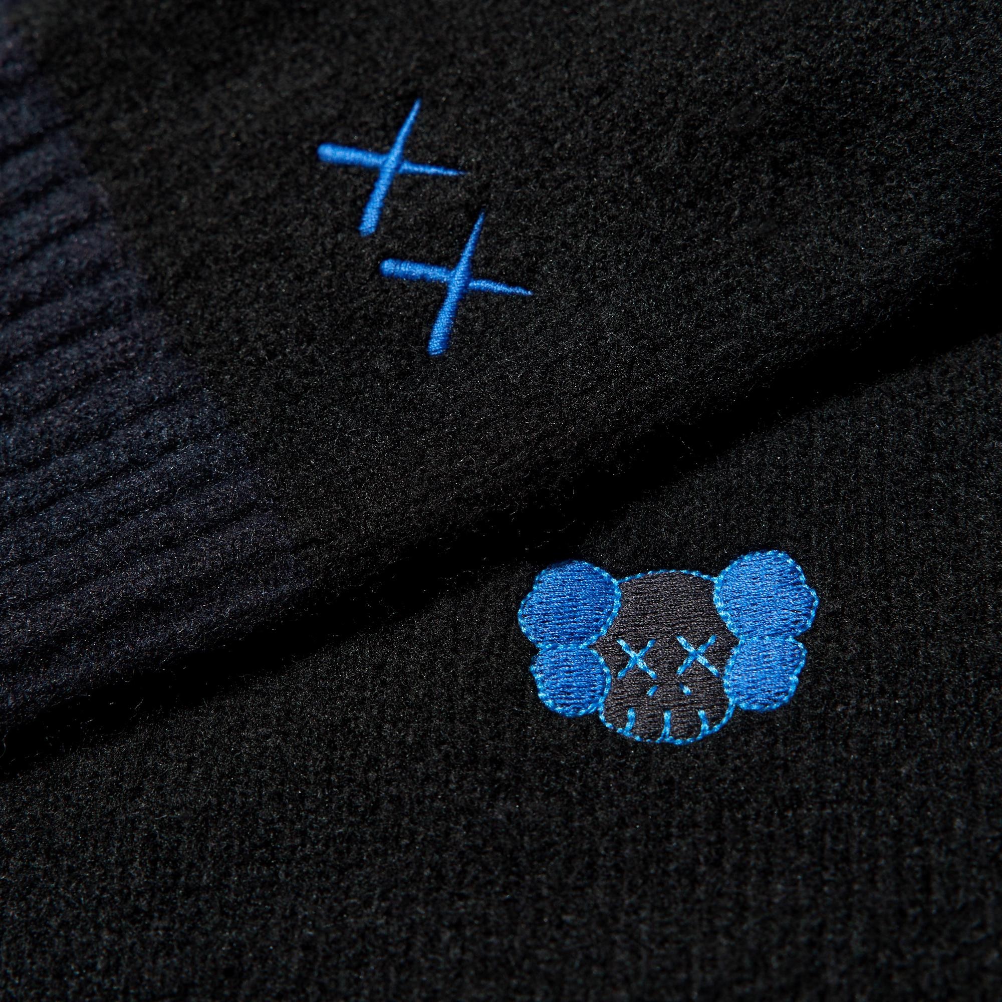 На левой стороне груди и на манжете левого рукава вышита вышивка от KAWS. Слегка закруглённый, простой крой.