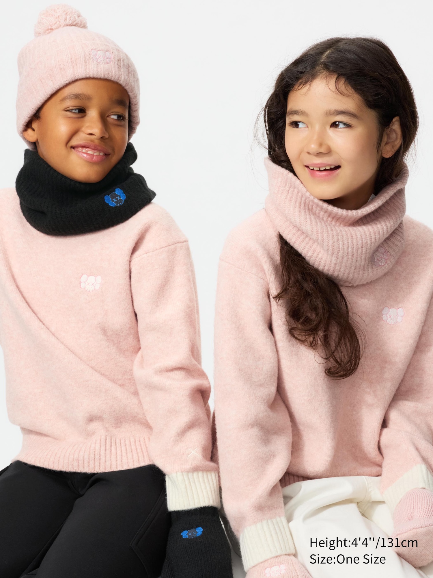 Ribbed 'HEATTECH' fleece with embroidered KAWS signature character design worn by two children wearing pink KAWS sweaters.