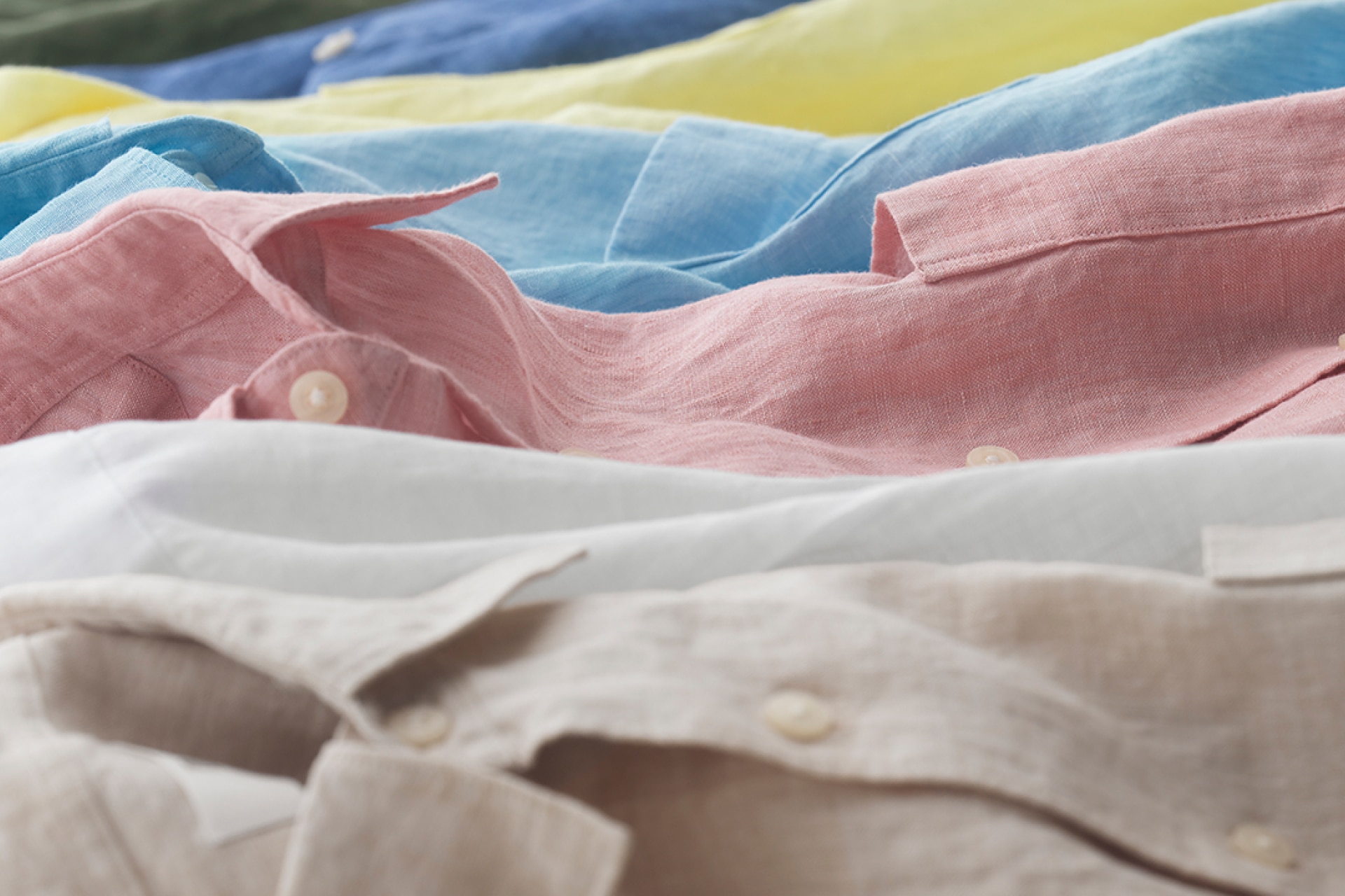Linen shirts close up showing colors brown, white, pink, blue, and yellow