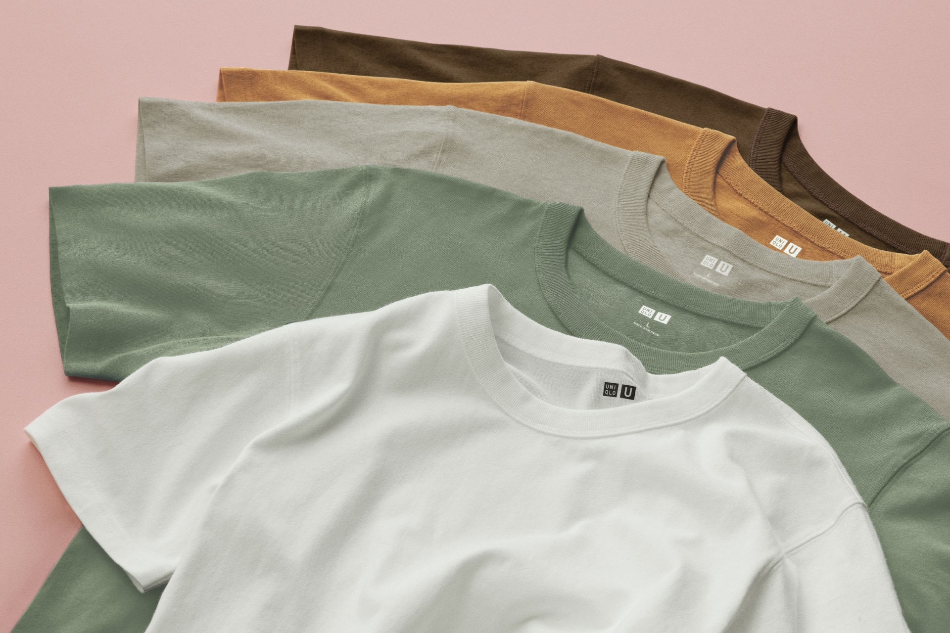 Layers of t-shirts in colors white, green, beige, orange, and brown
